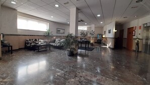 A spacious lobby with a marble floor, seating areas, and potted plants. - HOTEL AVENIDA (El Morell)