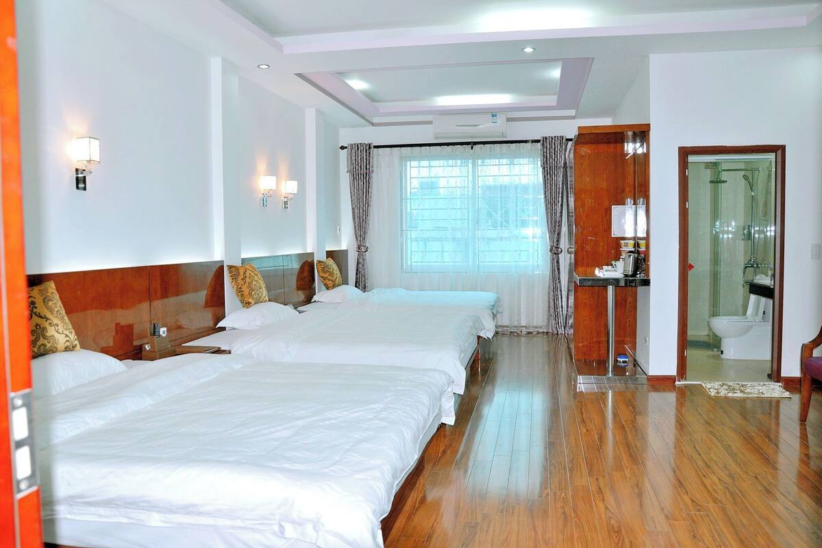 A hotel room with two beds, a bathroom, and a view of the outside.