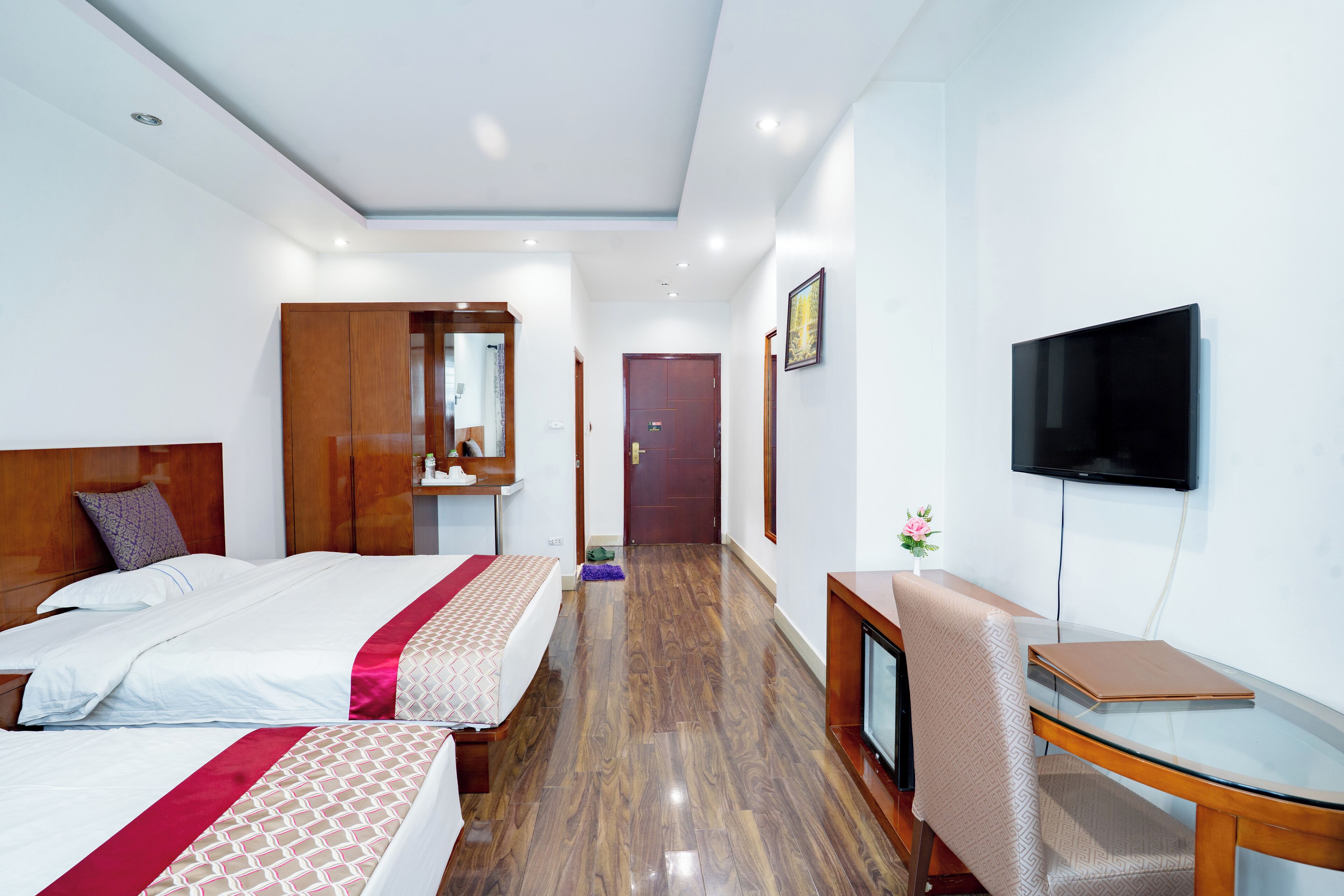 Habitación de hotel con dos camas, televisión, escritorio y armario de madera.