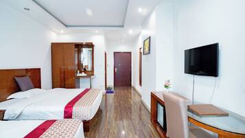 Habitación de hotel con dos camas, televisión, escritorio y armario de madera.