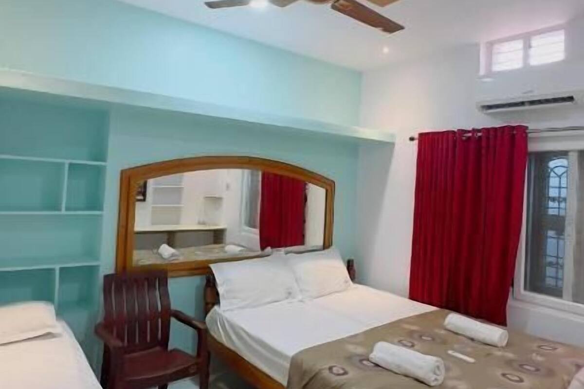 Una habitación de hotel con cama, una silla, un escritorio y un ventilador de techo.
