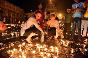 Un grupo de personas en un espacio al aire libre con numerosas velas encendidas en el suelo.