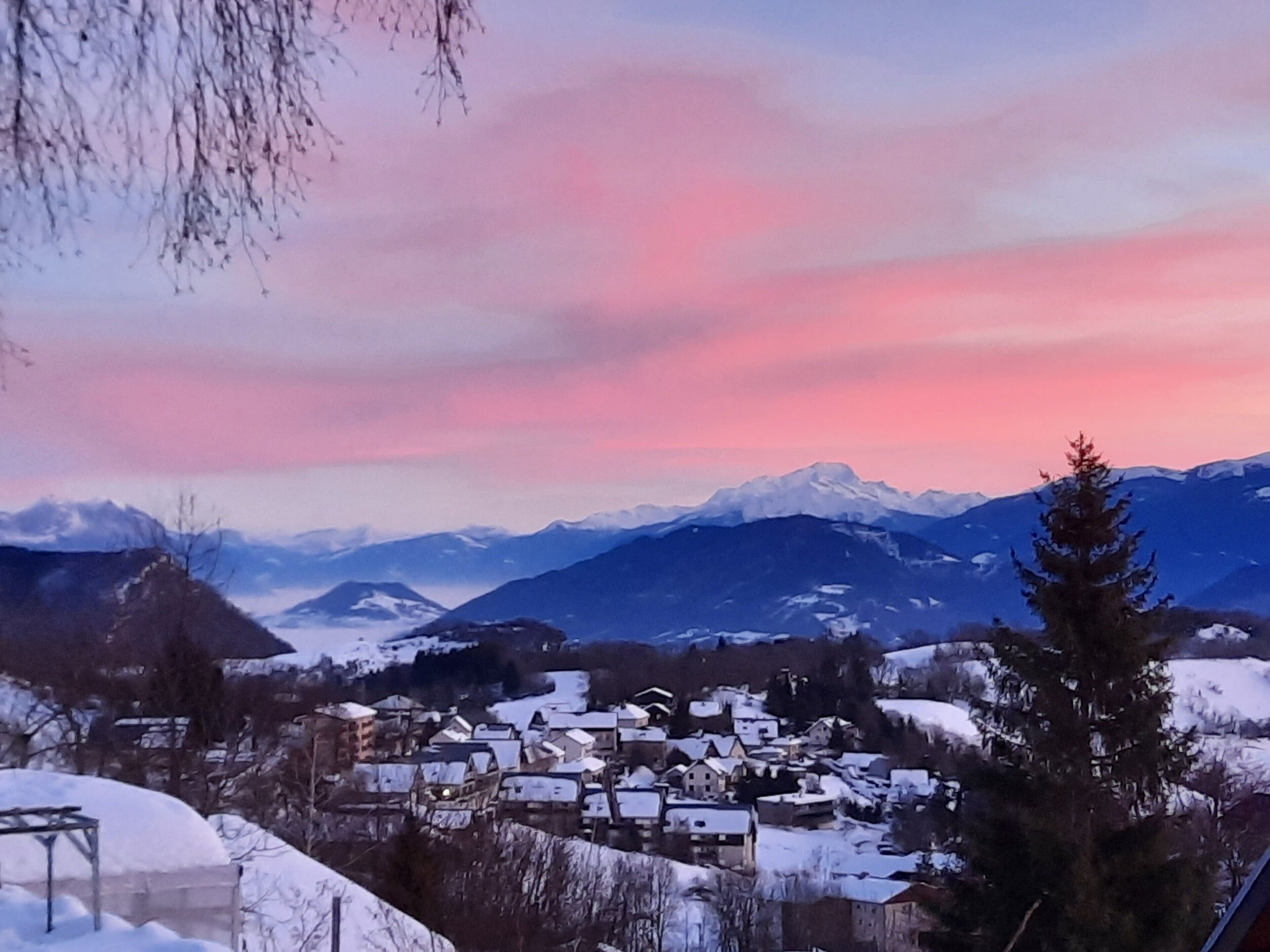 A snow-covered village with houses and mountains in the background.