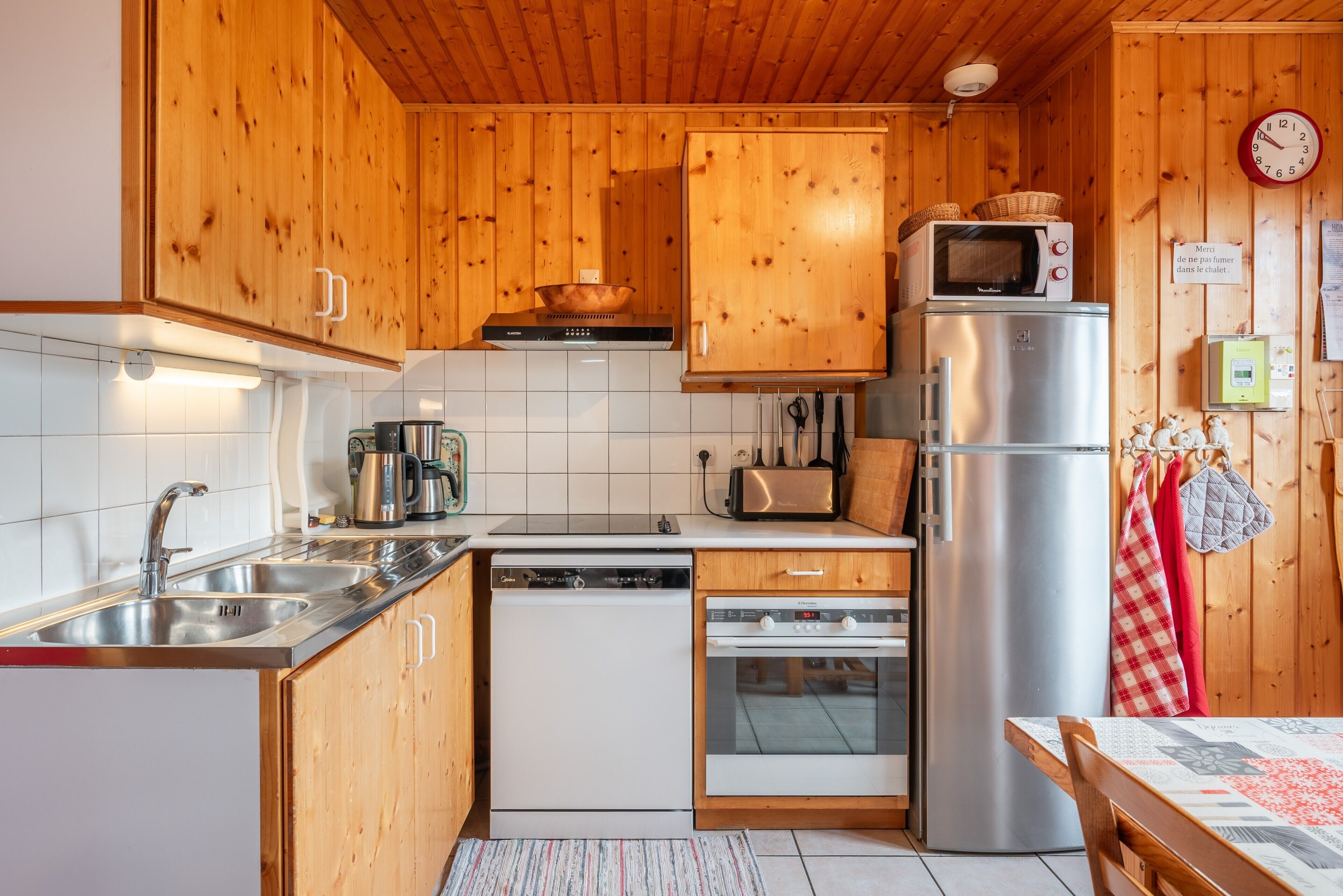 Eine Küche mit Holzausstattung, Edelstahlgeräten, einer Mikrowelle, einem Toaster und einem Kühlschrank.