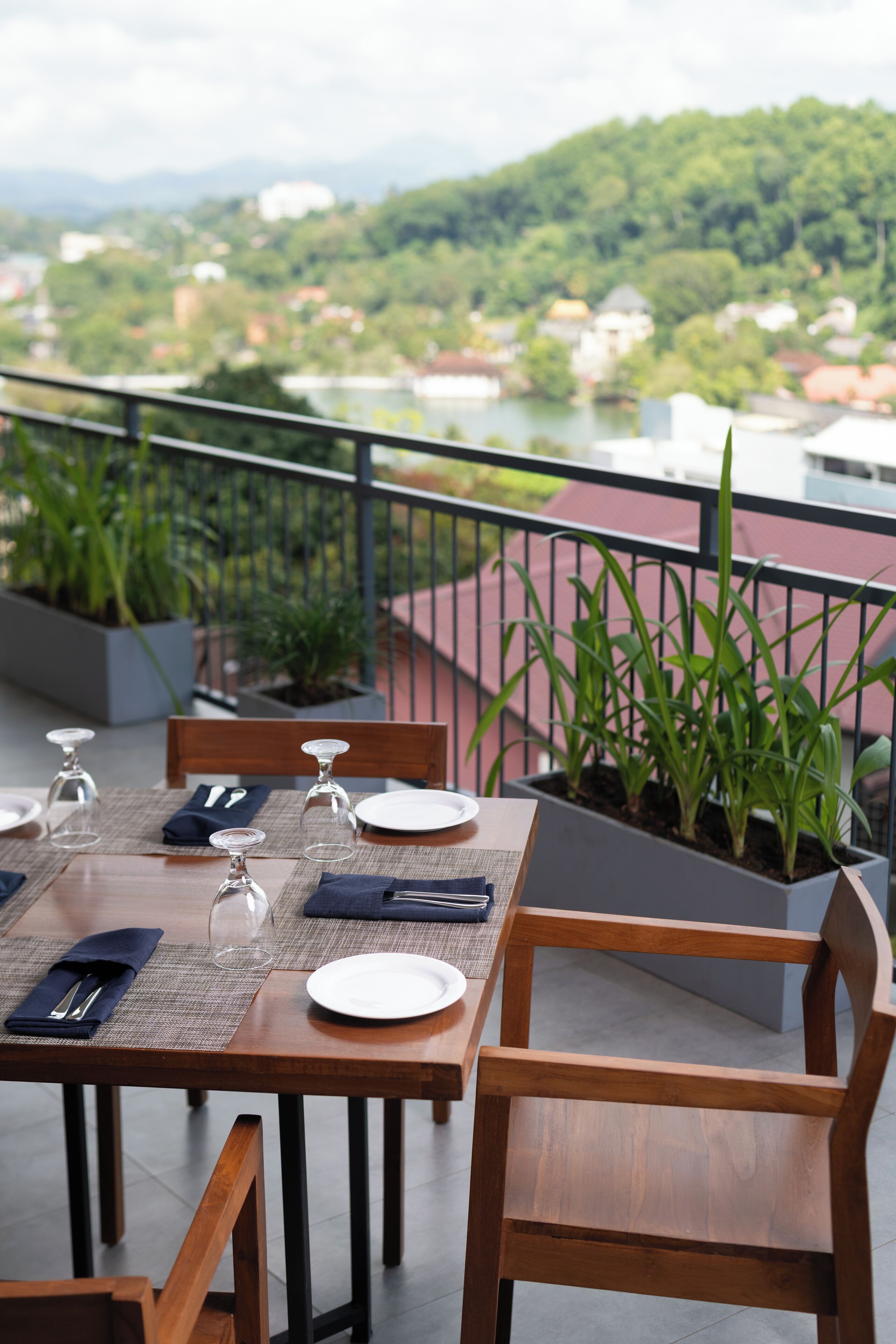 A dining table set with plates, glasses, and cutlery, overlooking a scenic view of a river and mountains.