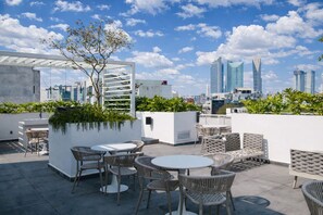 A rooftop terrace with outdoor seating, a pergola, and a view of the city skyline. - Modern loft on Monterrey Street in the heart of Roma Norte. Perfect for up to 3 guests, with a fully equipped kitchen, sofa bed, fast WiFi ideal for remote work, and easy self check-in. Shared rooftop and laundry in the building. Walk to cafés, parks (Cuauhtémoc)