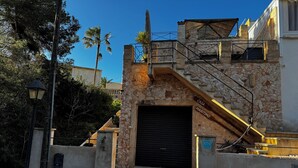 Un edificio de piedra con una puerta de garaje negra, una escalera con barandilla amarilla y un letrero que dice "CASA MARITIMO".