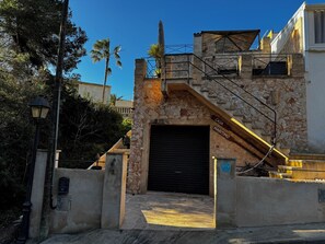 Ein Steinhaus mit einer schwarzen Garagentür, einer Treppe mit gelber Handlauf und einem Schild mit der Aufschrift 'CASA MARITIMO'.