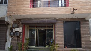 A building with a tiled facade, a set of steps leading to a glass entrance, and several potted plants. - Roomshala Hotel Rose Residency (New Delhi)