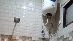 A bathroom with a toilet, a shower, and a hand dryer mounted on the wall. - Roomshala Hotel Rose Residency (New Delhi)