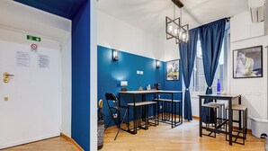 A modern kitchen with blue walls, a wooden floor, and a bar area with stools. - VIVILO COLLECTION - Marche 54 Apartment (Close to Via Veneto) (Roma)