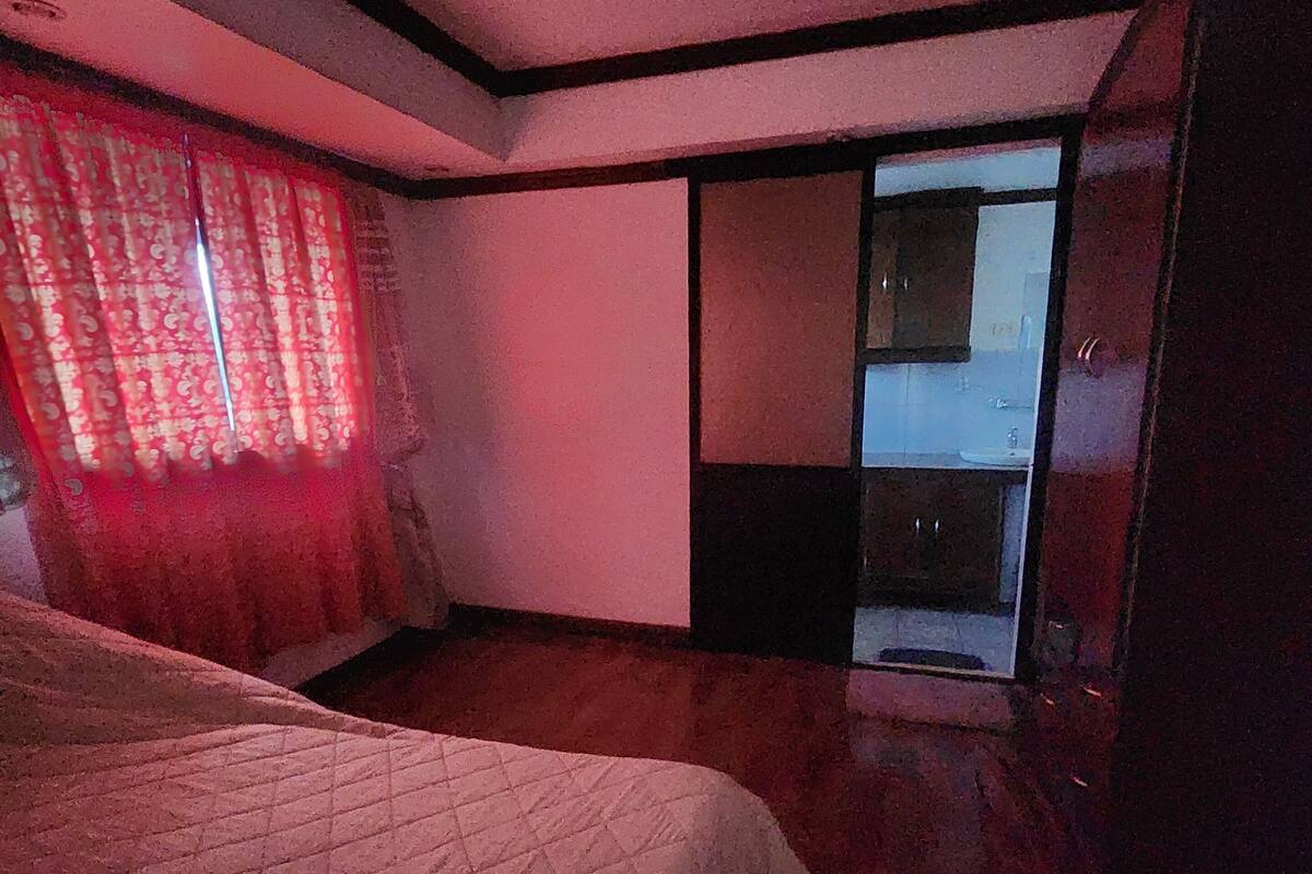 A bedroom with a bed, a wardrobe, and a bathroom visible through a sliding door.
