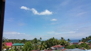 A coastal town with houses, palm trees, and a clear blue sky.