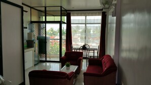 A room with a dining table and two red sofas, a water dispenser, and a view of the outside.
