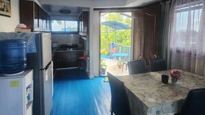 A compact kitchen with a refrigerator, sink, and cabinets, leading to a dining area with a table and chairs.