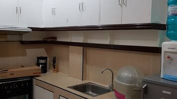 A kitchen with white cabinets, a stainless steel sink, a refrigerator, and a water dispenser.