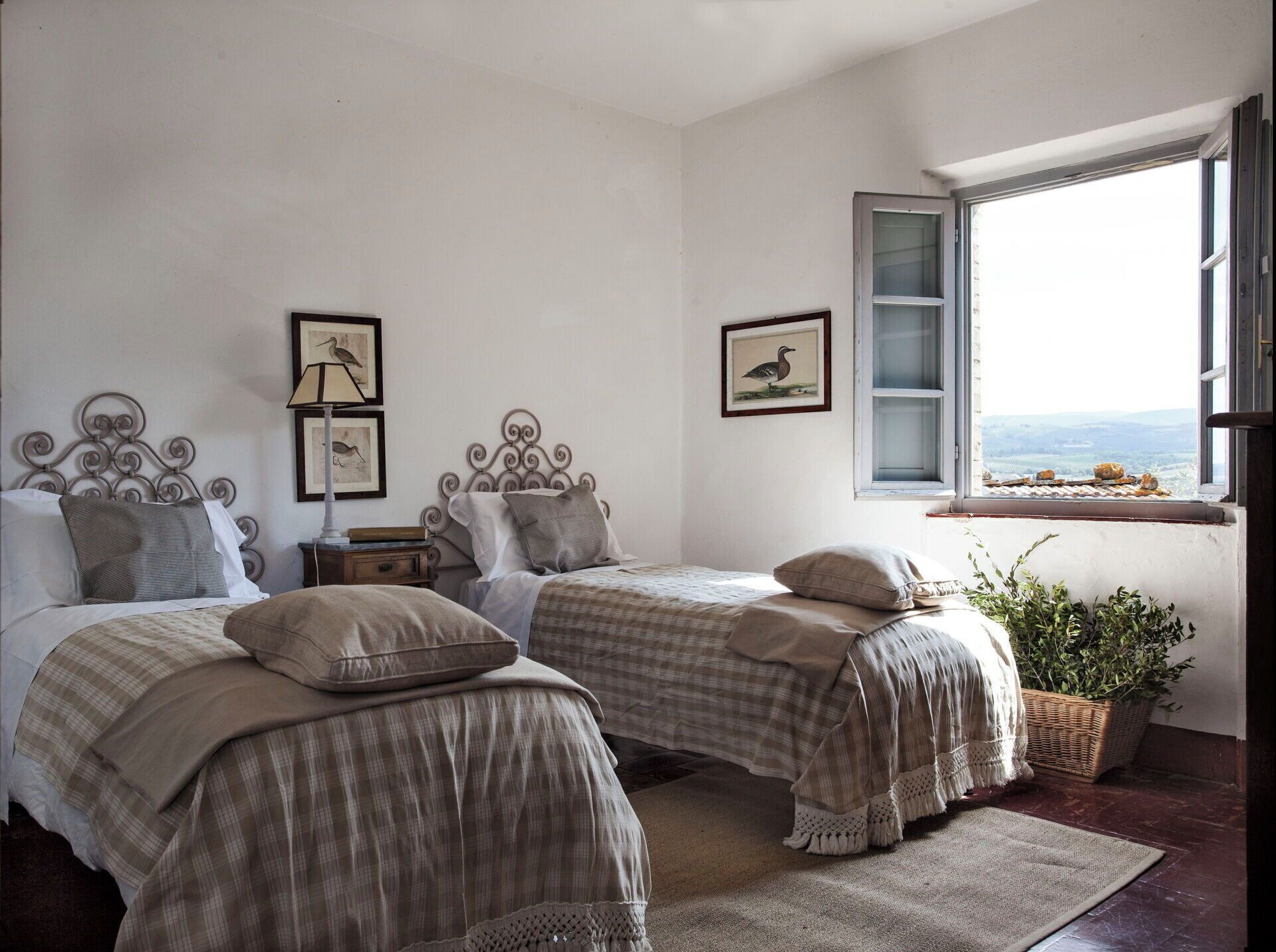 Un dormitorio con dos camas, una ventana con vistas y cuadros enmarcados en la pared.