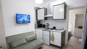 A compact living space with a kitchenette, a sofa, and a television. - Charming Camden Town Retreat with Garden – Walk to Market & Transport (London)
