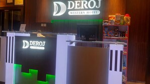 The reception area of the DEROJ Western Hotel with a modern design, including a reception desk and a shelf with various items. - Deroj Western Hotel (Benin City)