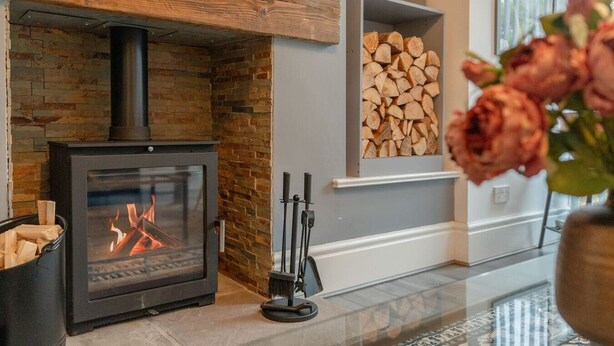 A modern fireplace with a stone wall, a wood-burning stove, and a fire burning inside. - Short walk to Colne cafés, restaurants with fireplace, free parking (Lancashire)