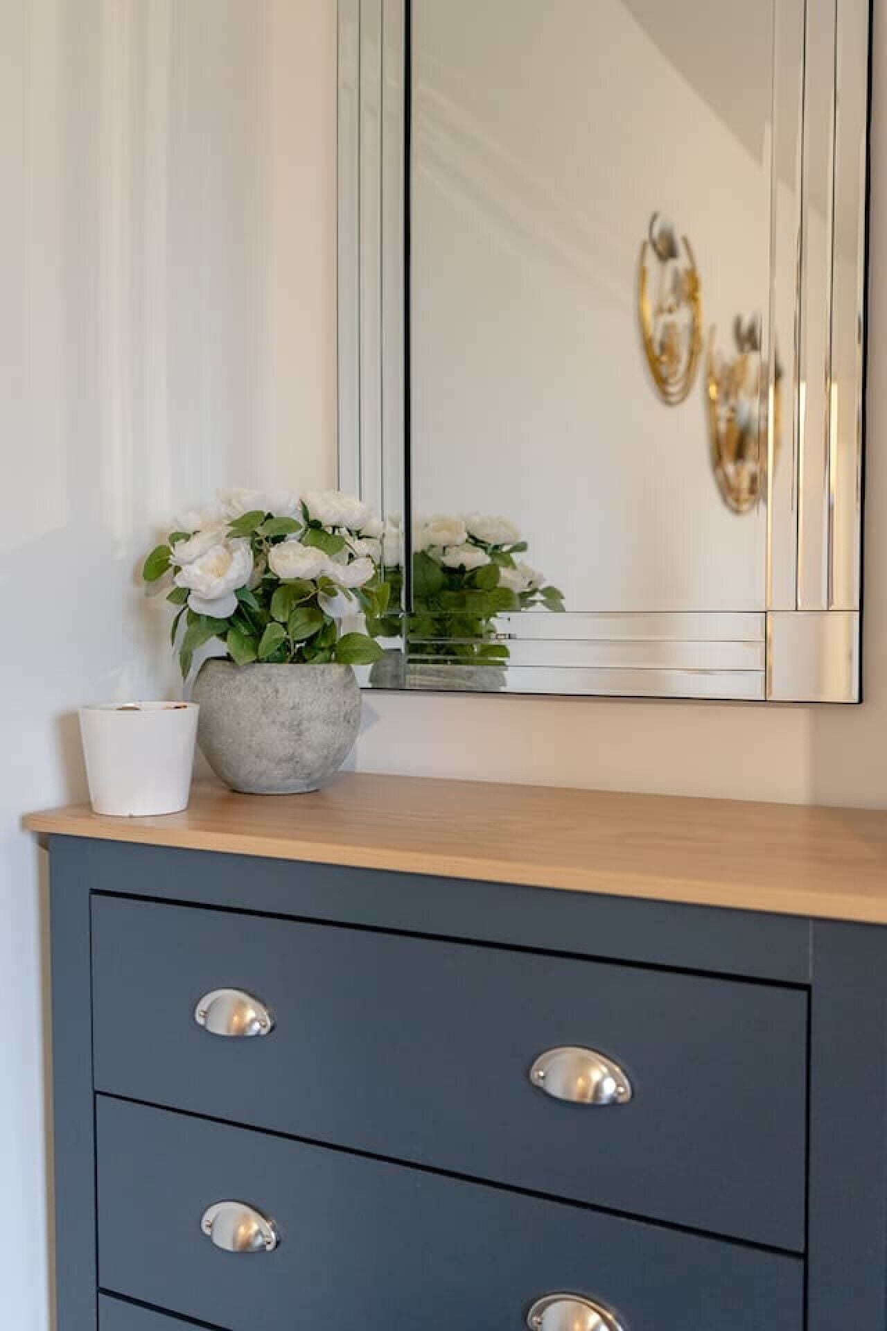 A wooden dresser with a grey cabinet and a mirror above it.