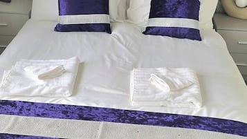 Una cama bien hecha con sábanas blancas, dos almohadas con estampado azul y blanco a rayas y un corredor de cama azul y blanco a rayas.