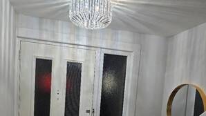 A white door with frosted glass panels, a small circular mirror on the wall, and a chandelier above. - Gem Place - A Home Away From Home (Hornchurch)