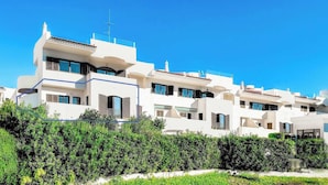 Une rangée de bâtiments modernes, blancs, dotés de balcons, qui font probablement partie d’un complexe résidentiel.