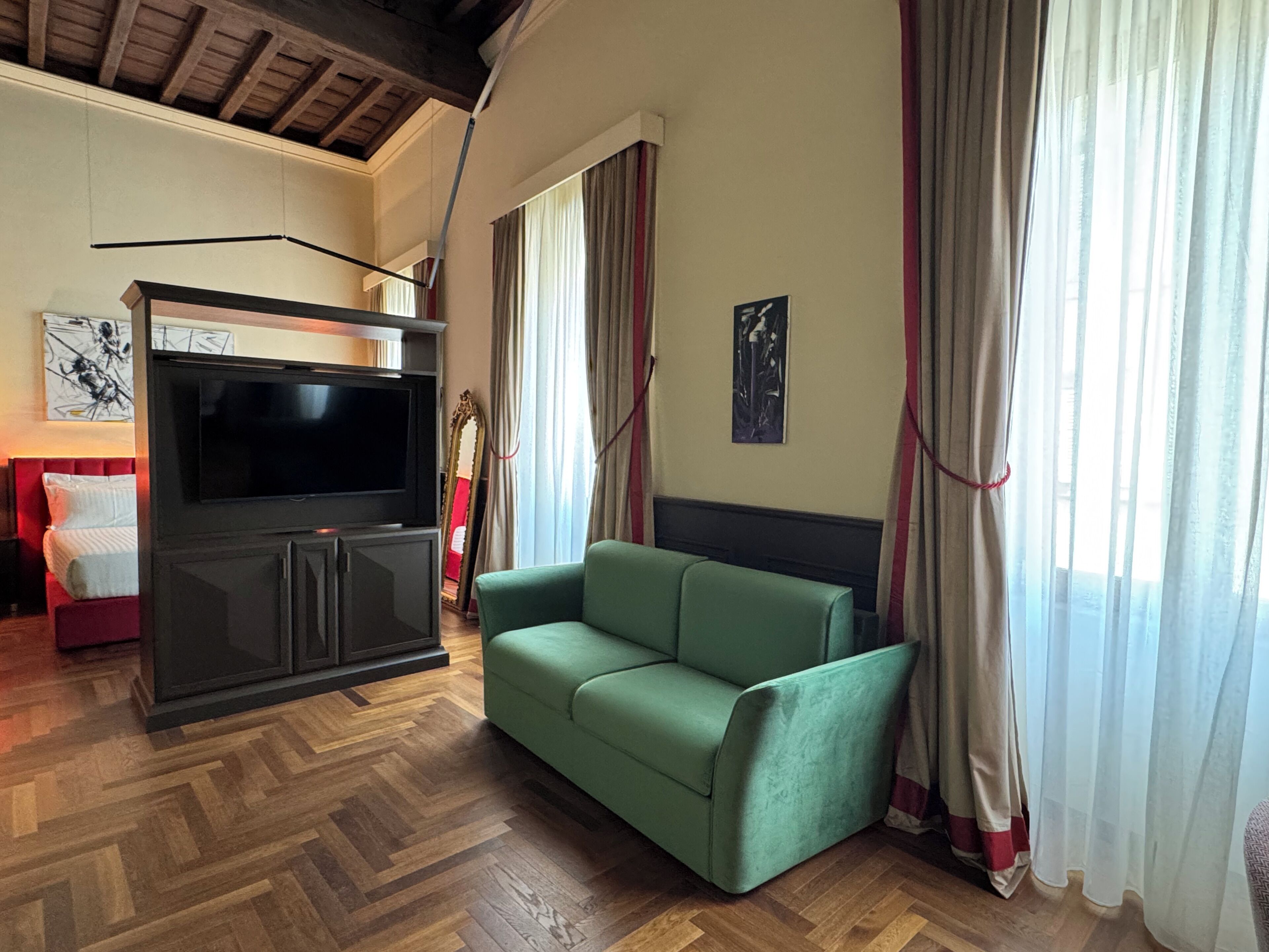 Un saló amb televisió, sofà, mirall i un quadre a la paret.