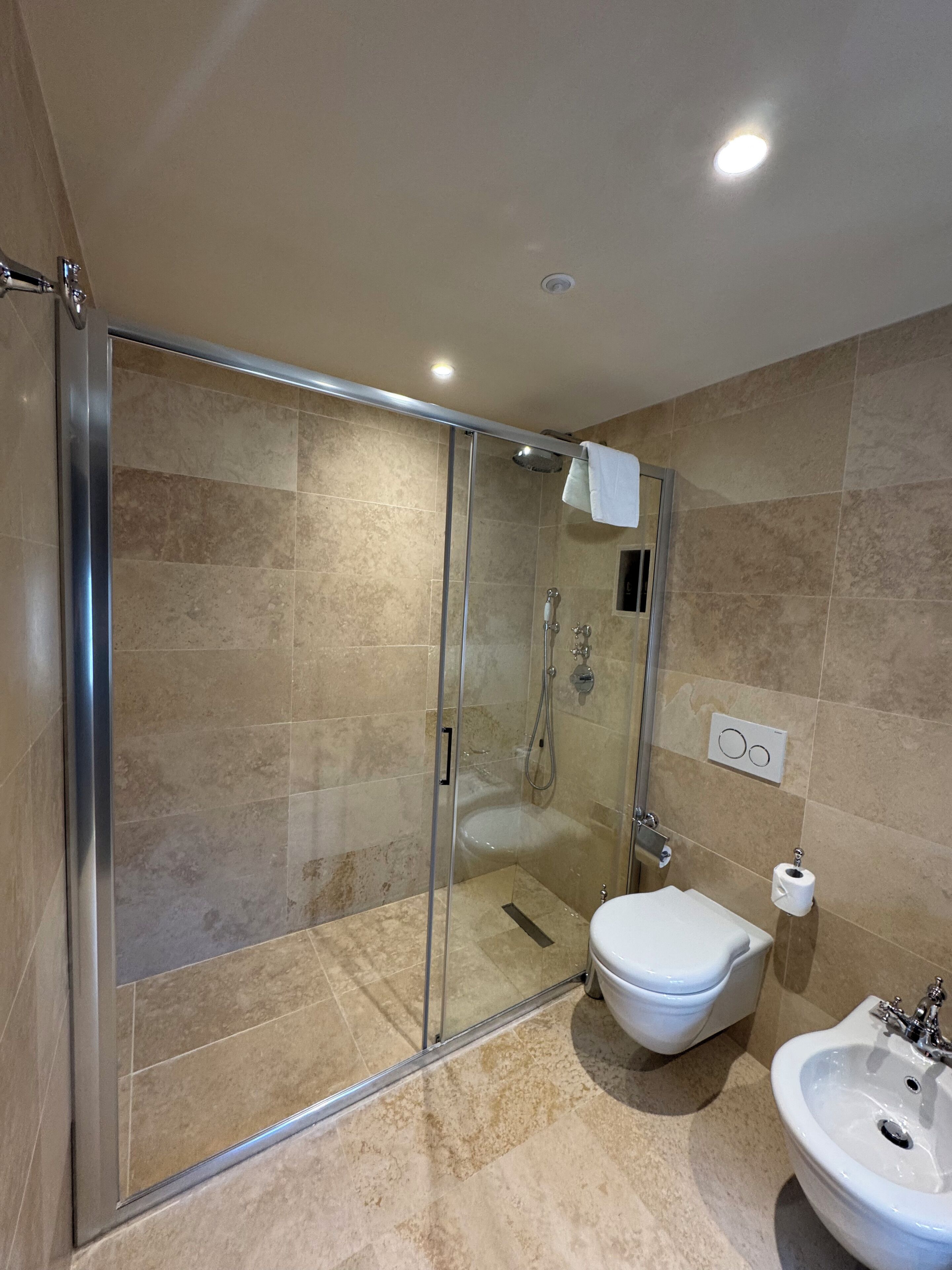 A modern bathroom with a glass-enclosed shower, a toilet, and a sink.