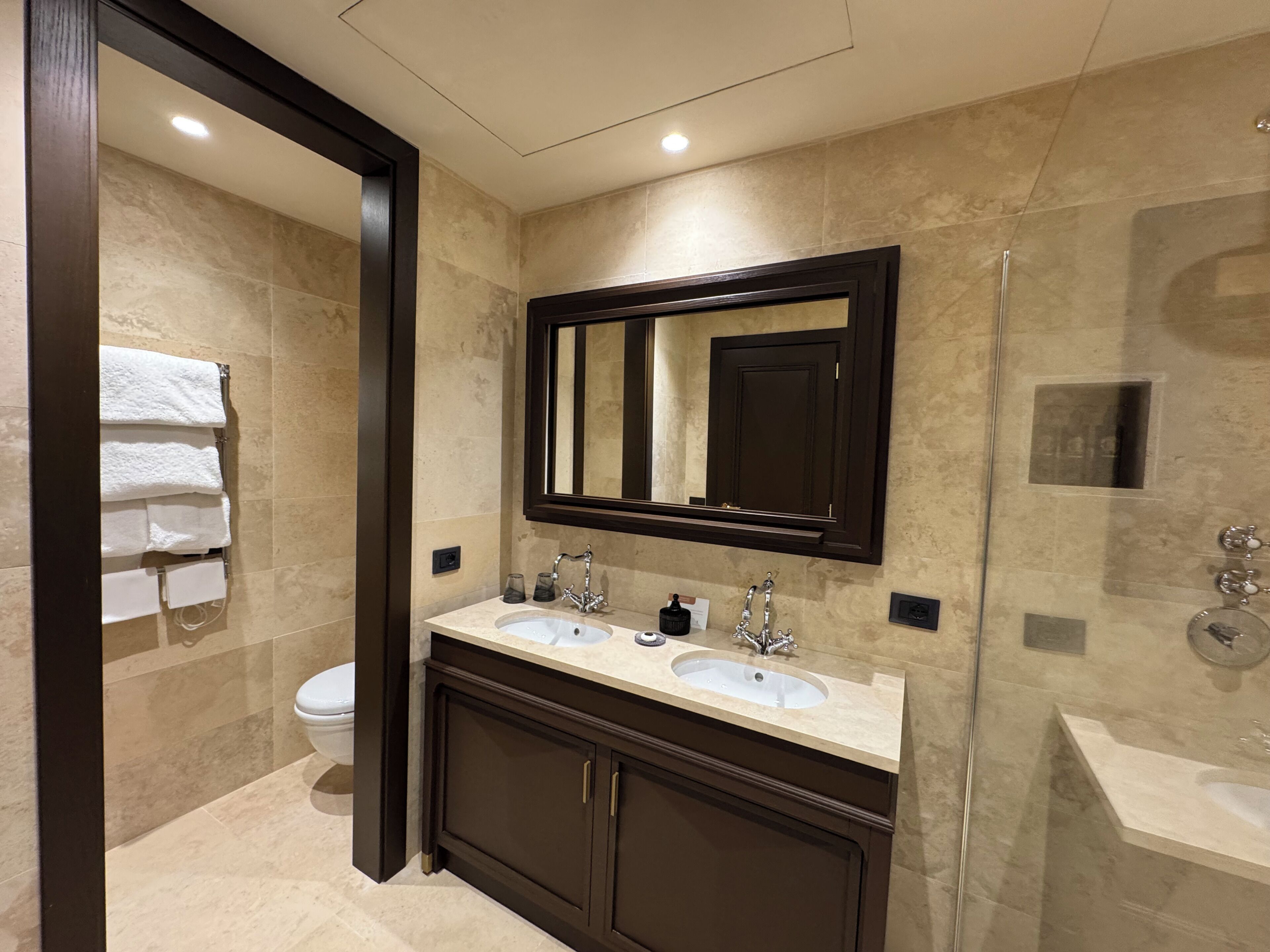 Un baño moderno con lavamanos doble, un espejo grande y cabina de ducha con mampara de vidrio.