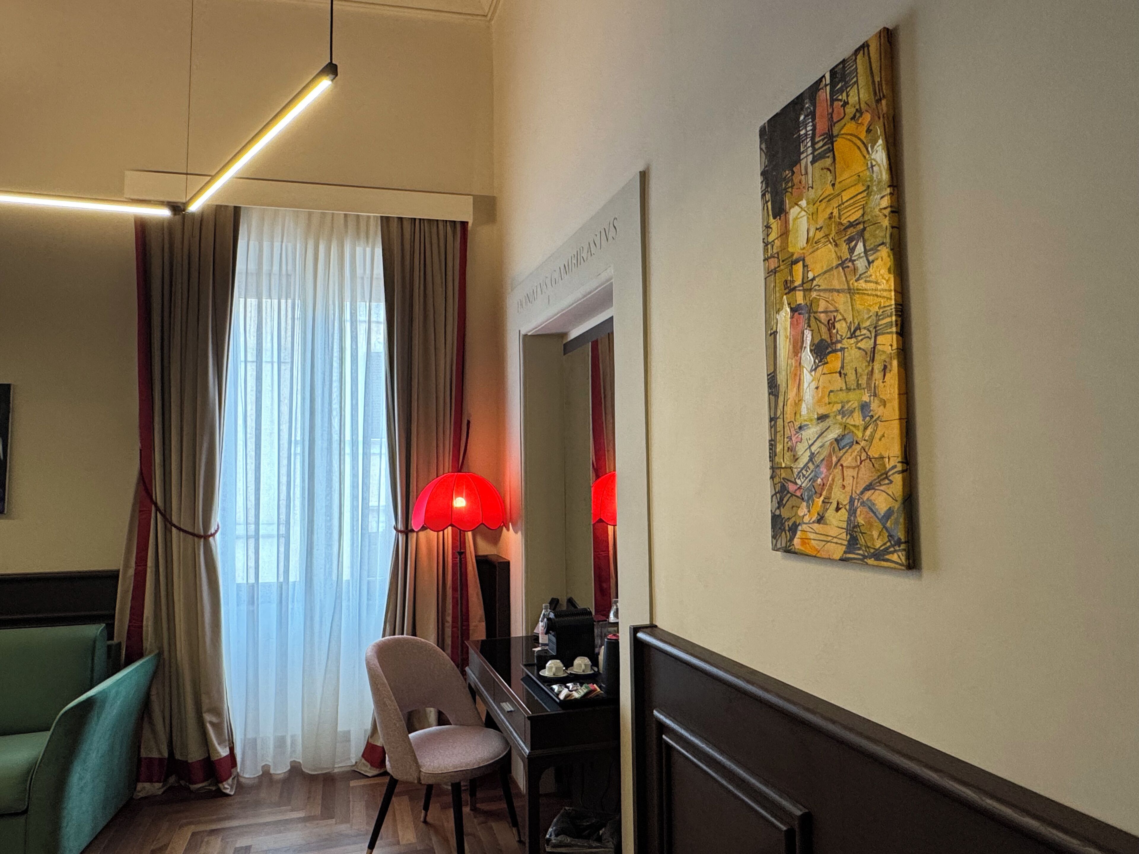 Une chambre d’hôtel équipée d’un bureau, d’une chaise et d’un grand tableau abstrait accroché au mur.