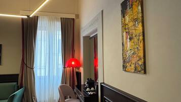 Une chambre d’hôtel équipée d’un bureau, d’une chaise et d’un grand tableau abstrait accroché au mur.
