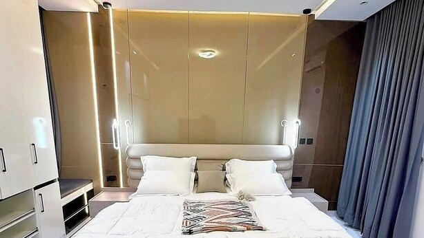 Ein modernes Hotelzimmer mit einem großen Bett, einem Nachttisch, einem Kleiderschrank und einer Sitzecke.