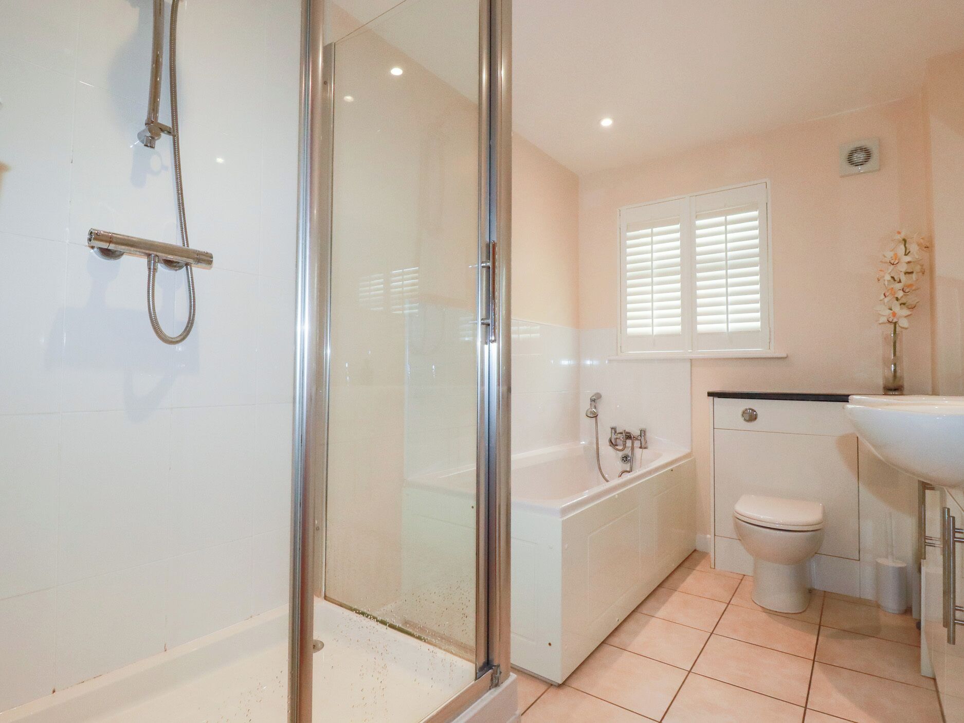 A modern bathroom with a glass shower enclosure, a bathtub, and a toilet.