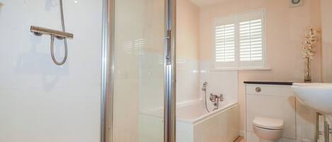 A modern bathroom with a glass shower enclosure, a bathtub, and a toilet.