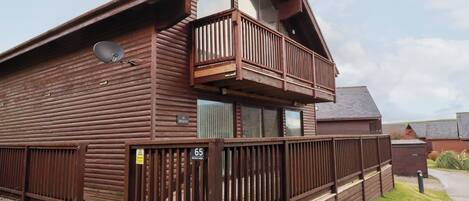 A two-story log cabin with a balcony, a satellite dish, and a sign indicating it is Benasa Lodge.