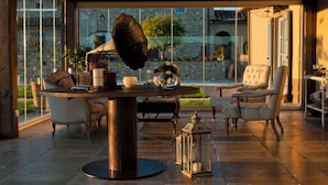 Een modern interieur met een ronde tafel, stoelen en een groot raam met uitzicht op een stenen gebouw en groen.