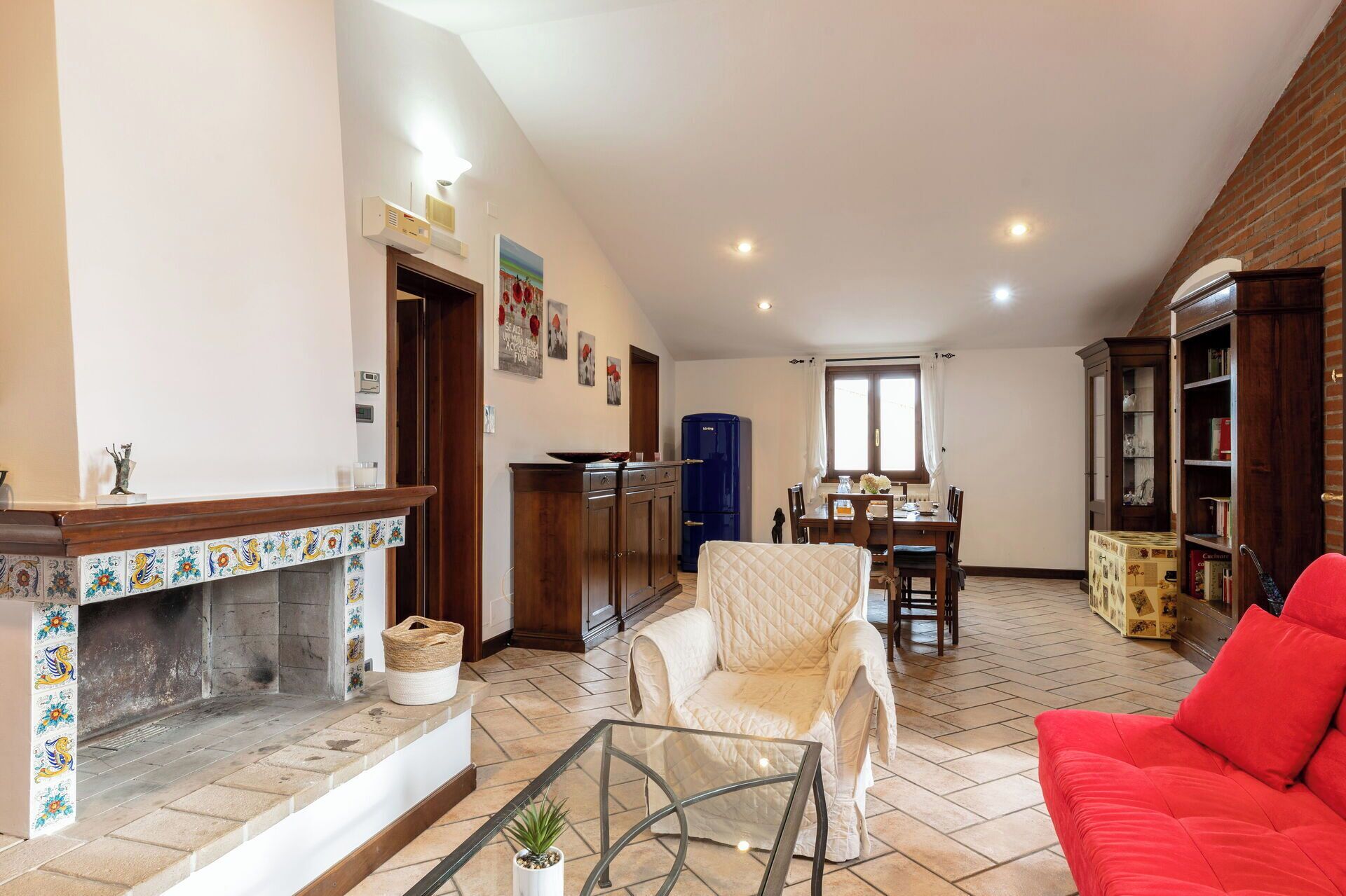 Una sala de estar con chimenea, un comedor y un sofá rojo.