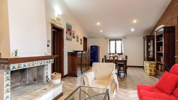 Una sala de estar con chimenea, un comedor y un sofá rojo.