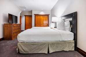 Une chambre d’hôtel avec un grand lit, une armoire en bois et un téléviseur.