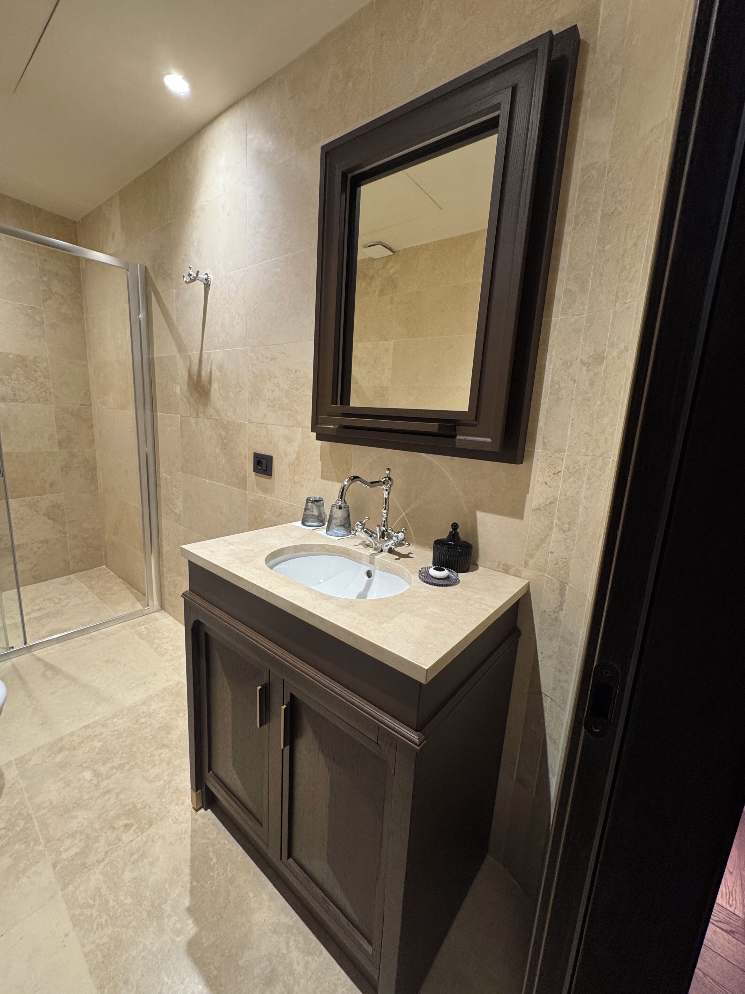 A bathroom with a sink, mirror, and shower.