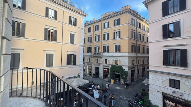A courtyard with buildings, outdoor seating, and a shop. - Palazzo Gambirasi Aparthotel Roma (Rome)