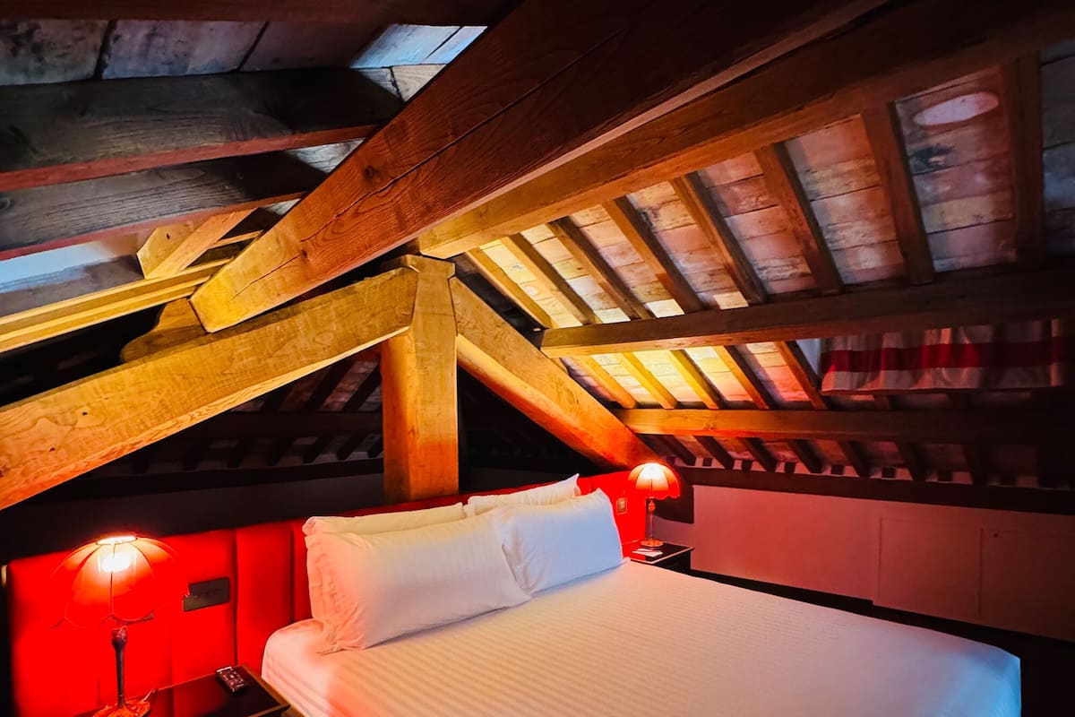Ein Schlafzimmer mit Holzboden, einem Bett, einem Nachttisch und einer roten Lampe.