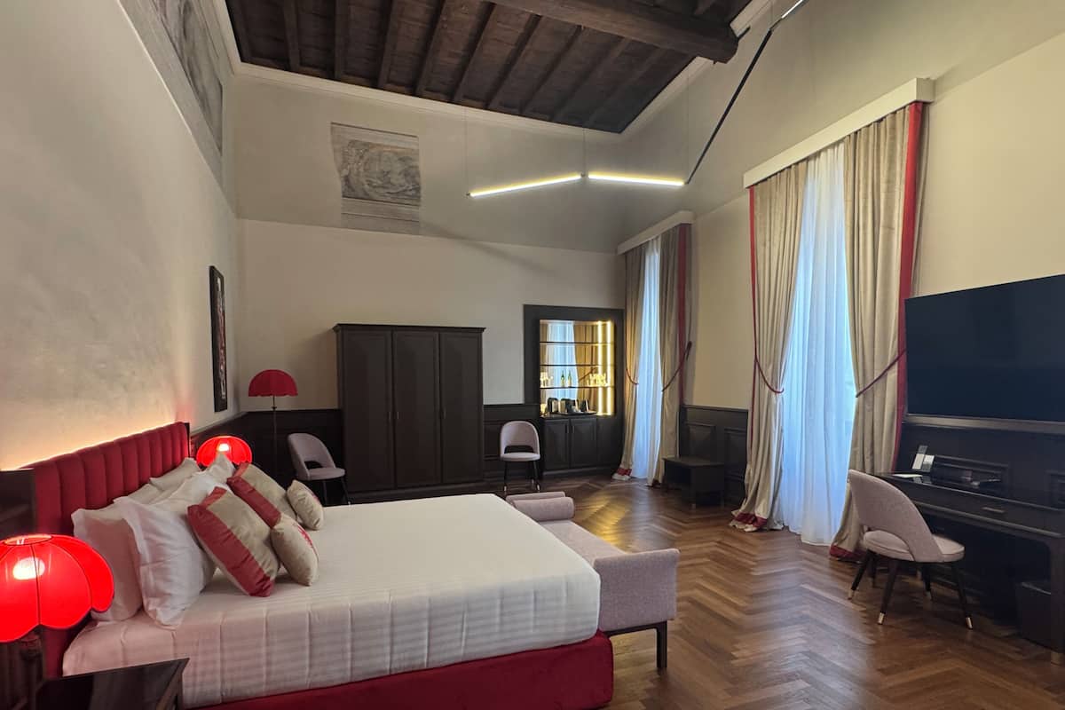 Ein Hotelzimmer mit einem großen Bett, einem Schreibtisch, einem Fernseher und einem Kleiderschrank.