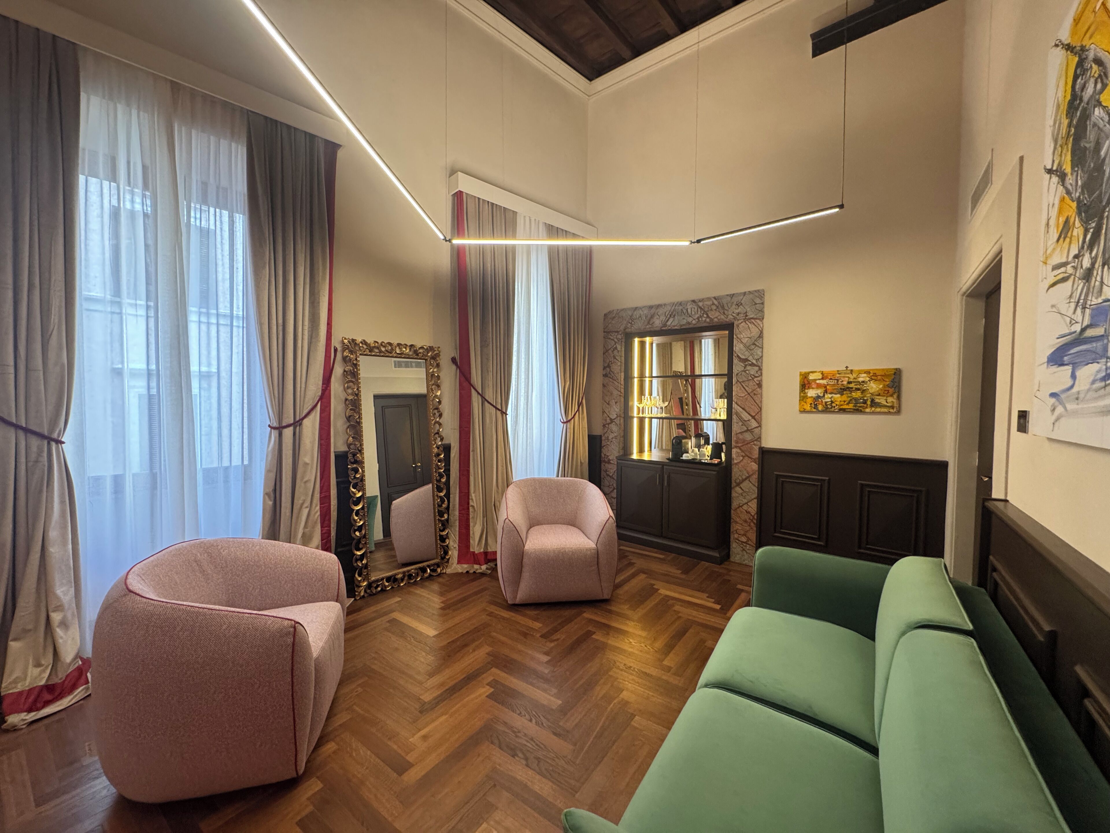 Ein modernes Wohnzimmer mit Fischgrätparkett, einem großen Spiegel und einem grünen Sofa.
