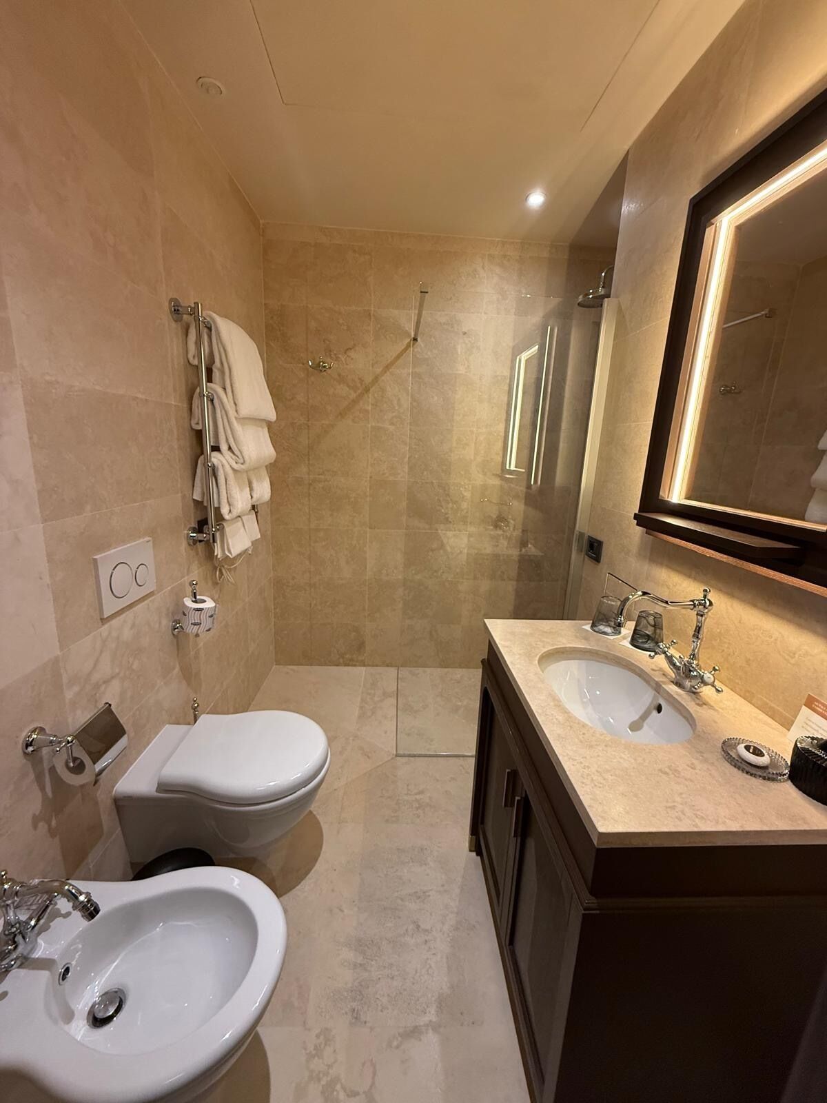 Ein modernes Badezimmer mit zwei Waschbecken, einer Toilette, einer Dusche und einem großen Spiegel.