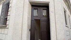 A building entrance with a dark brown door, a small window with bars, and a number '12' on the wall. - Palazzo Gambirasi Aparthotel Roma (Rome)