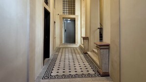 A hallway with a tiled floor, an elevator, and a staircase with a handrail. - Palazzo Gambirasi Aparthotel Roma (Rome)