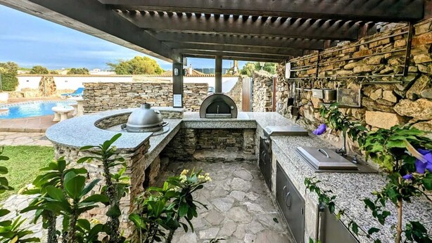 An outdoor kitchen area with a stone countertop, a pizza oven, and a grill. - Casa Zahora - extended families' first choice! (Cádiz)